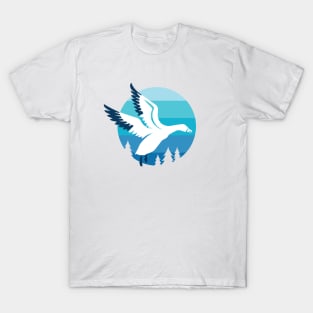 Snow Goose flying over pine trees T-Shirt